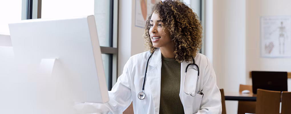 doctor-desktop Adult female doctor reviews patient records on desktop PC.