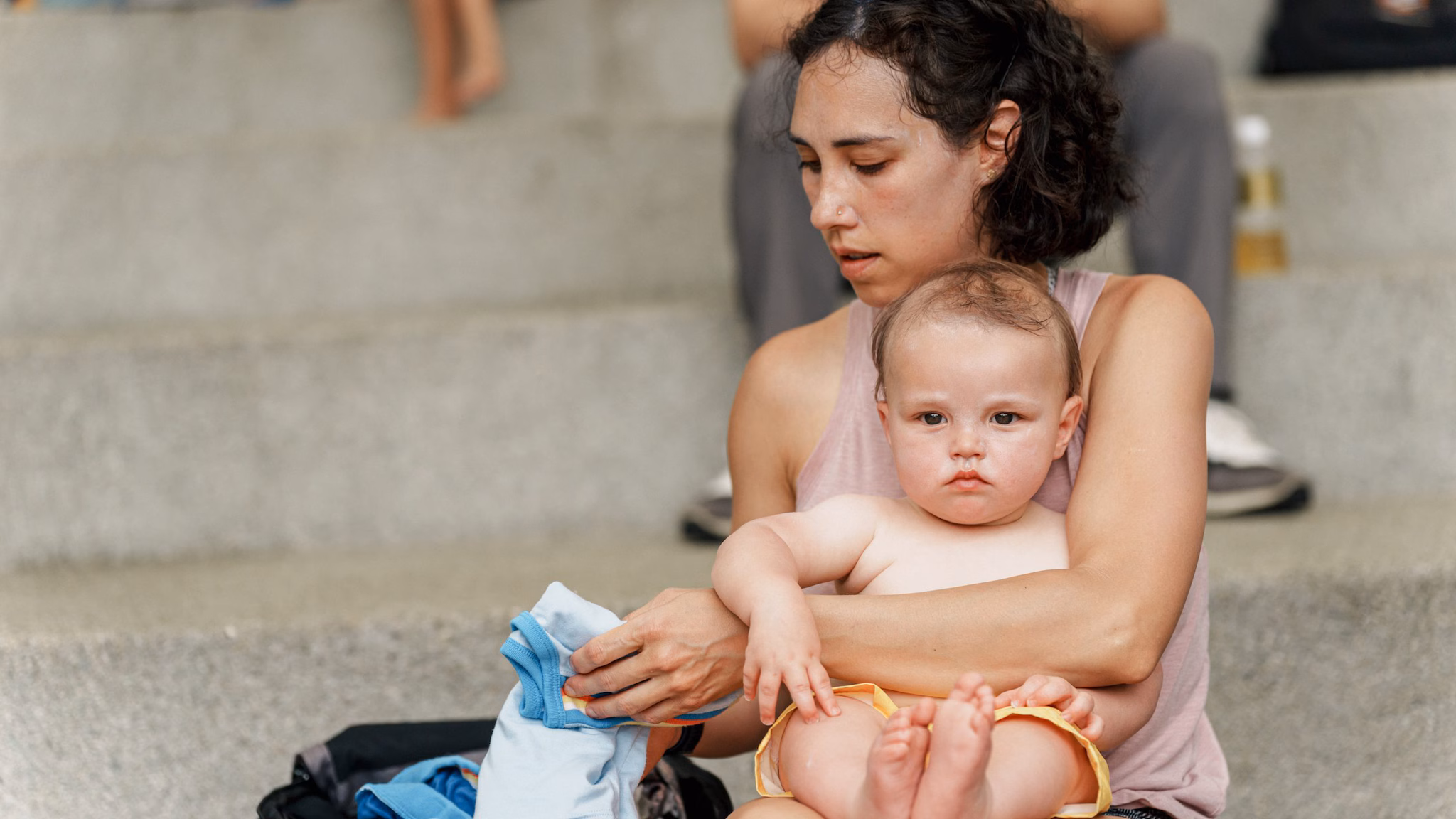Woman sits with toddler son on the stairs of an outdoor park. Woman sits with toddler son on the stairs of an outdoor park