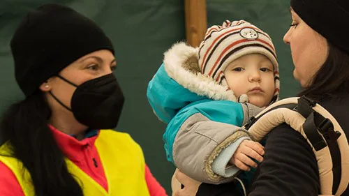 — title missing — Relief worker assisting a family at a shelter.