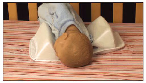The figure shows a simulated display using a doll in an infant sleep positioner with two bolsters, demonstrating how an infant's face can get trapped against the bolster, causing suffocation.