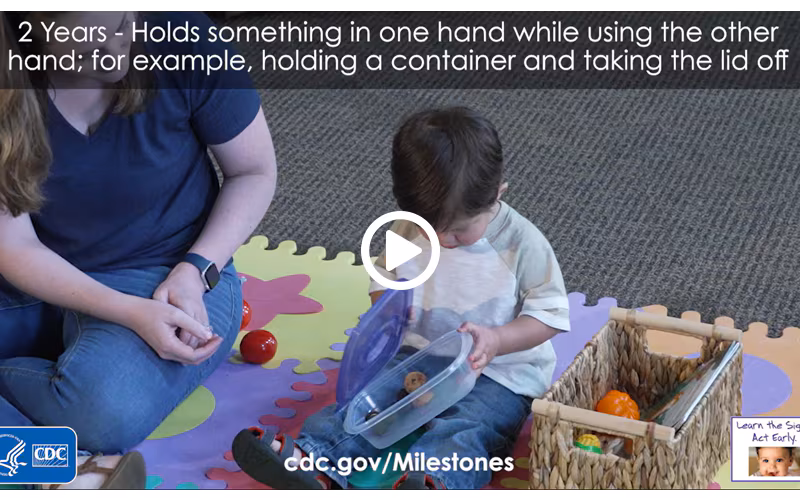 Holds something in one hand while using the other hand; for example, holding a container and taking the lid off