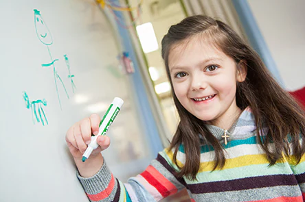 5 year old girl drawing on a board