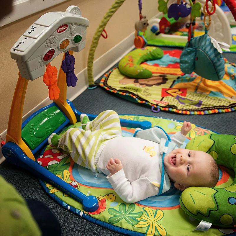 A baby plays with his toys while lying on his back
