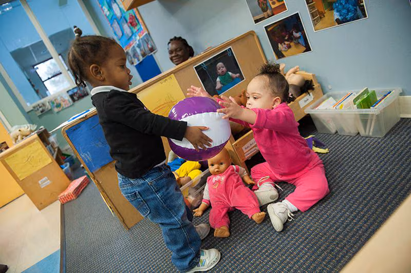 two girls play with a ball