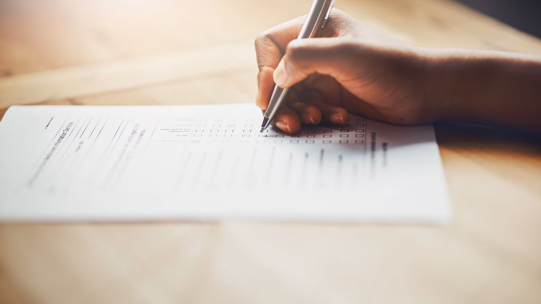 Hand with pen filling out a form.