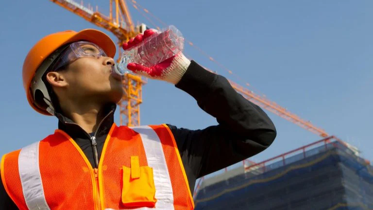 Heat stress construction worker Construction worker in safety gear drinking water