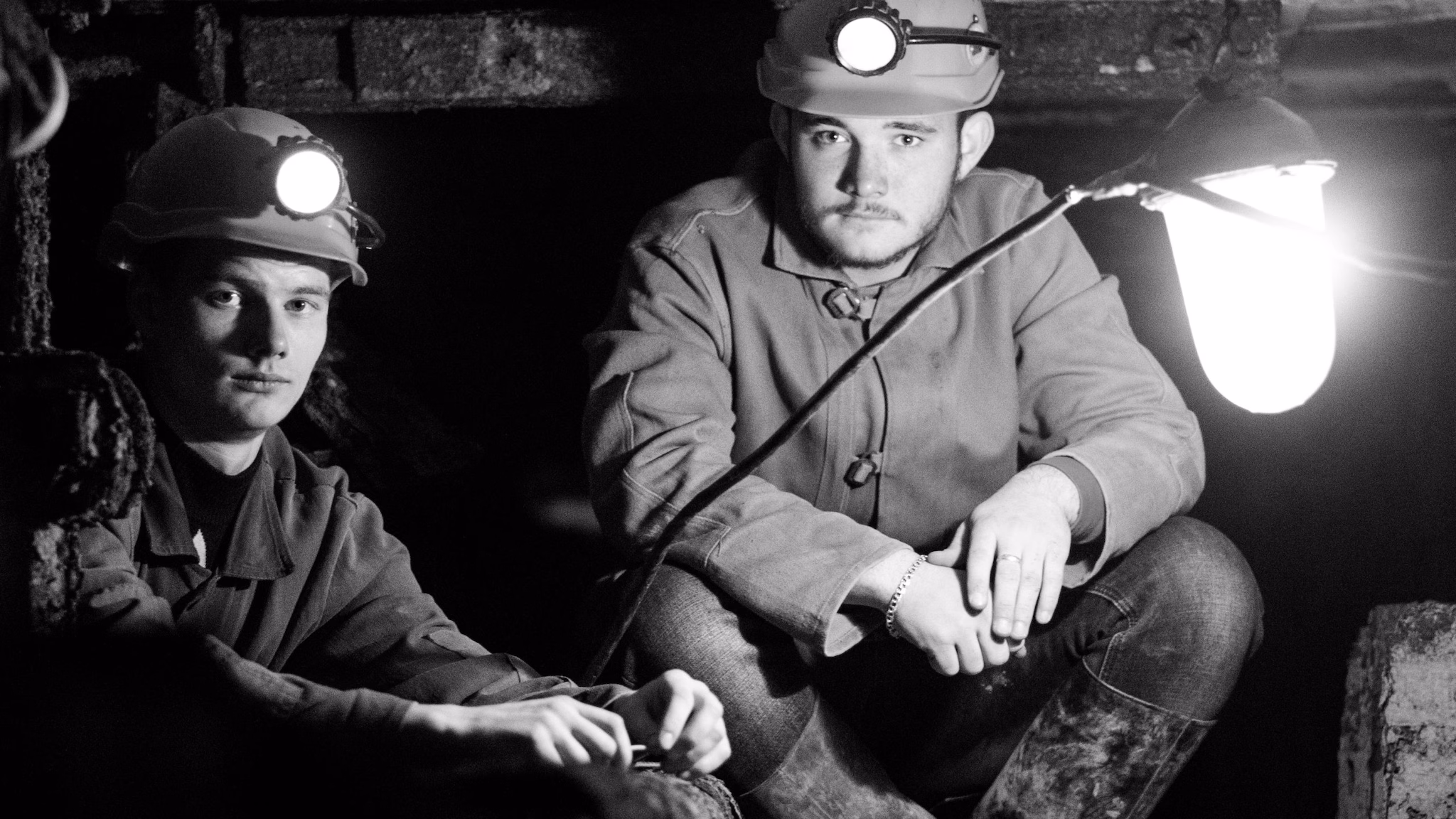— title missing — Two coal miners sitting in underground mine.