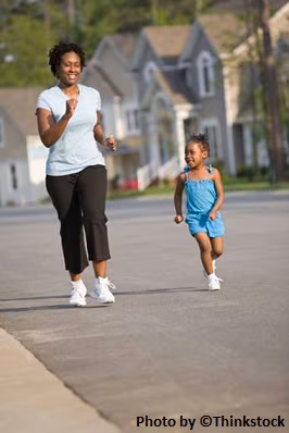 A mother and daughter smiling, jogging in a neighborhood