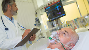 patient wearing oxygen mask on hospital bed with dr charting at bedside Patient in hospital bed, with doctor charting at the bedside