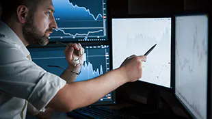 man Analyzing Screen small Man works in the office with multiple computer screens in index charts.