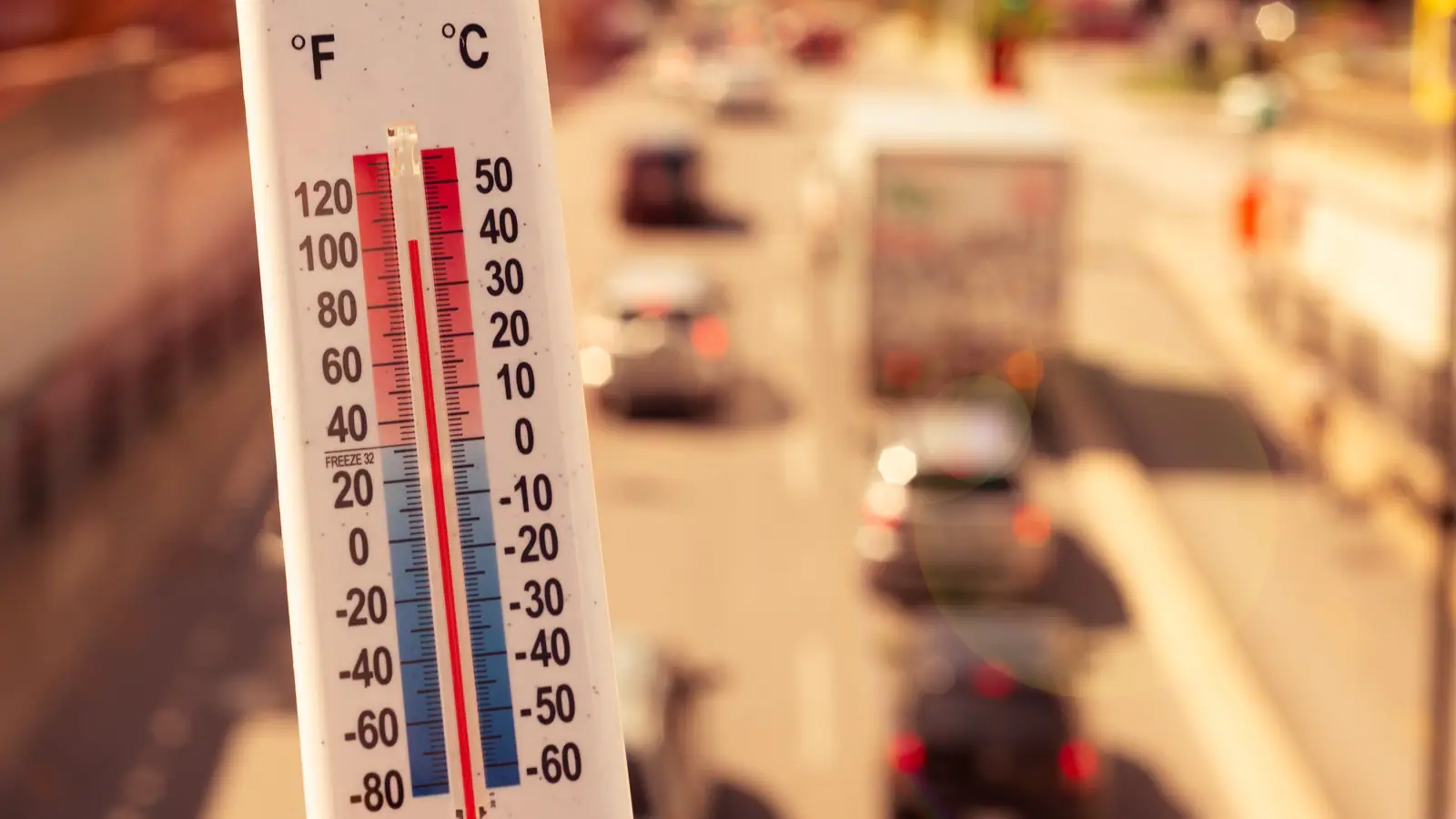 thermometer with high temperature on highway traffic background Extreme heat visualized in front of traffic with a thermometer.