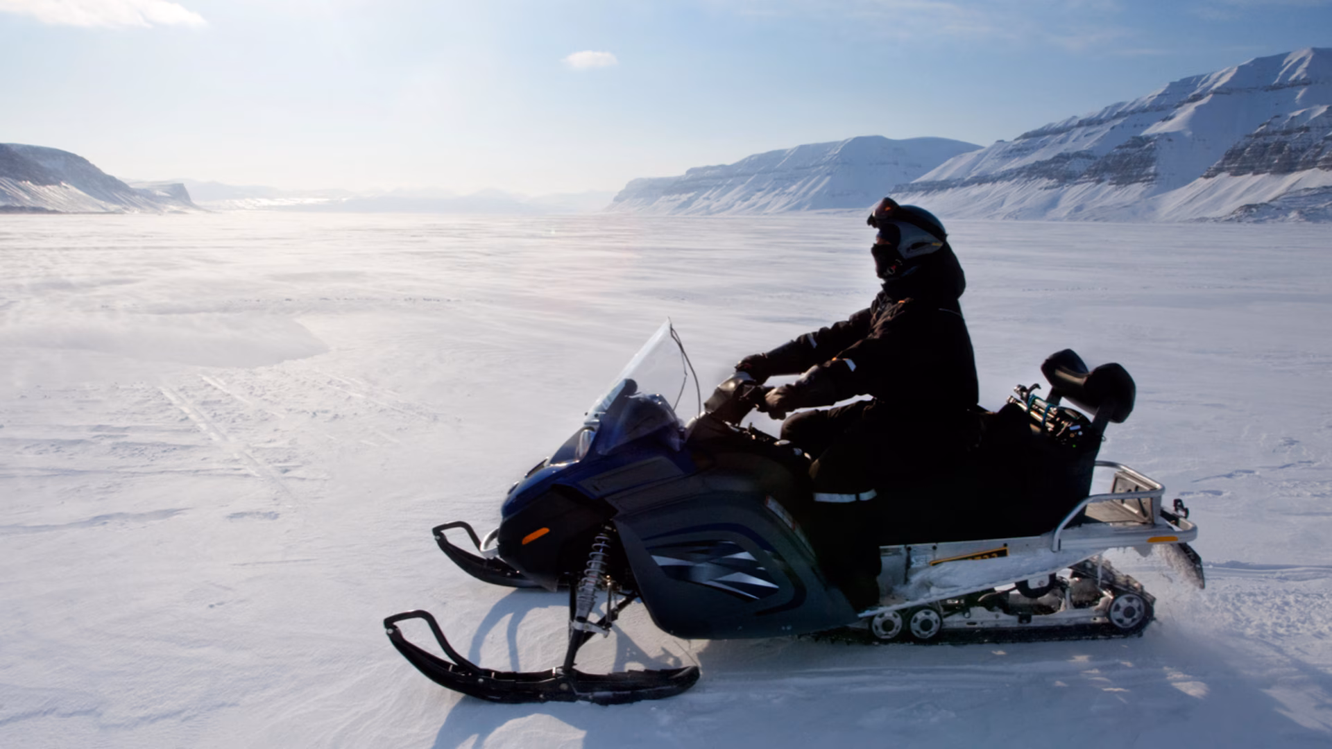 rider on snowmobile in frozen landscape Person riding snowmobile in the daylight in rural snow covered area