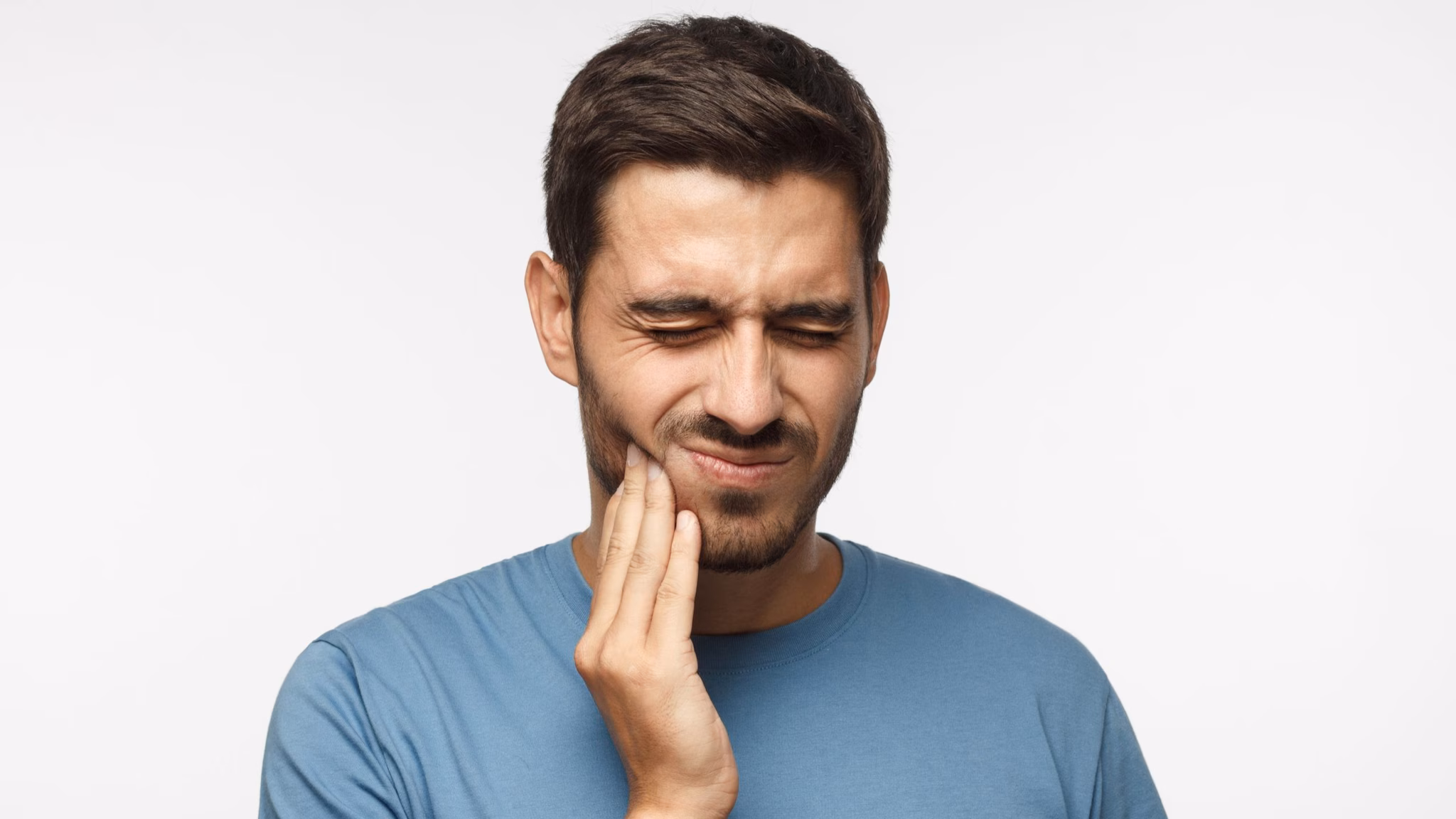 Adult male with tooth pain Adult male grimaces while touching jaw