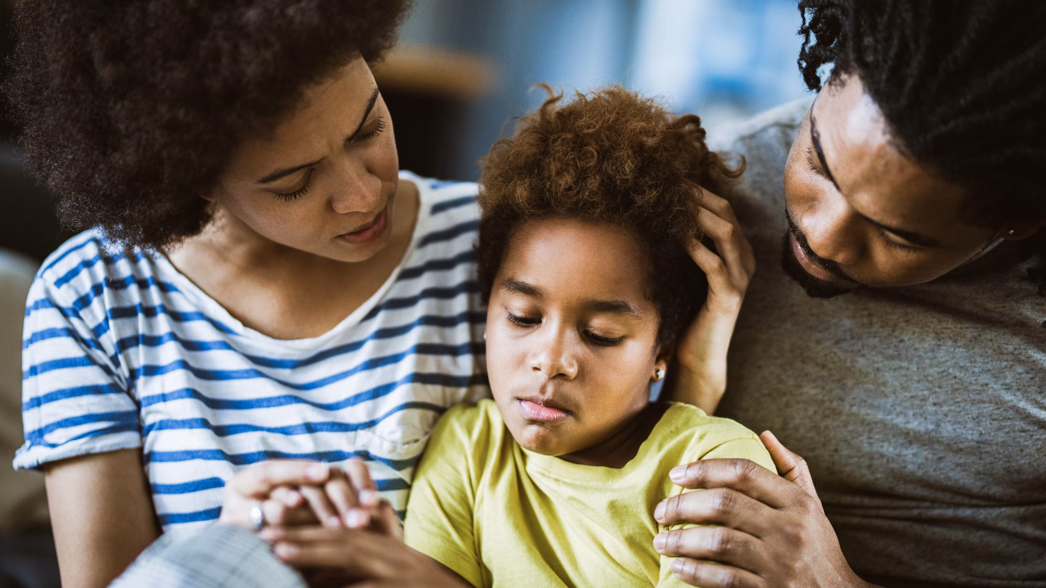 A mother and father comforting their child.