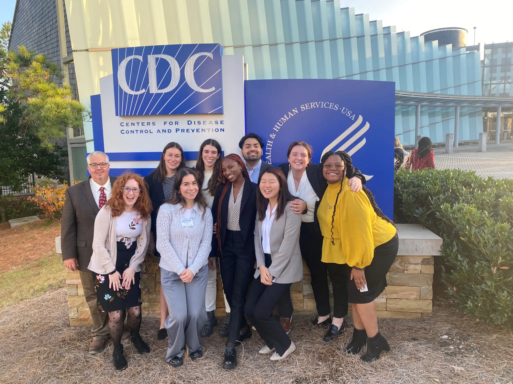Class of 2023 at HQ A group of associates smiles in front of the CDC headquarters sign.