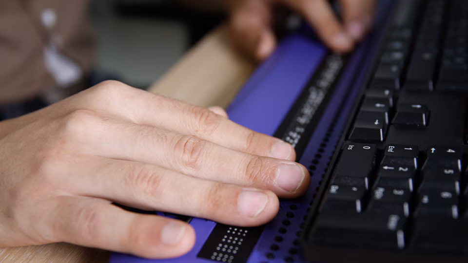 Close-up of white male hands typing on a computer keyboard.