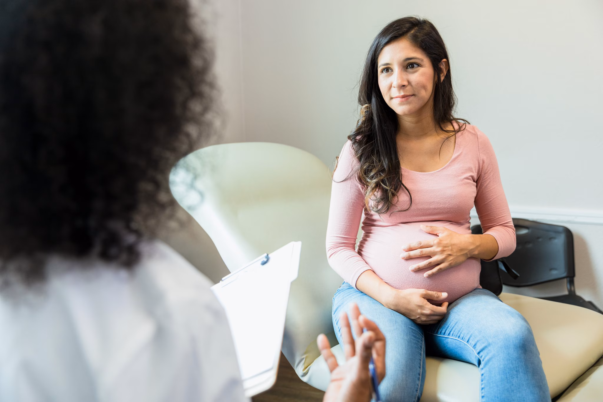 Pregnant Woman Talking with Doctor image 330 KB A standing healthcare provider is holding a chart and speaking with a sitting pregnant woman