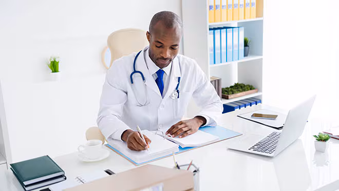Clinician checking reference documents A clinician sitting at a desk referring to some reference documents.