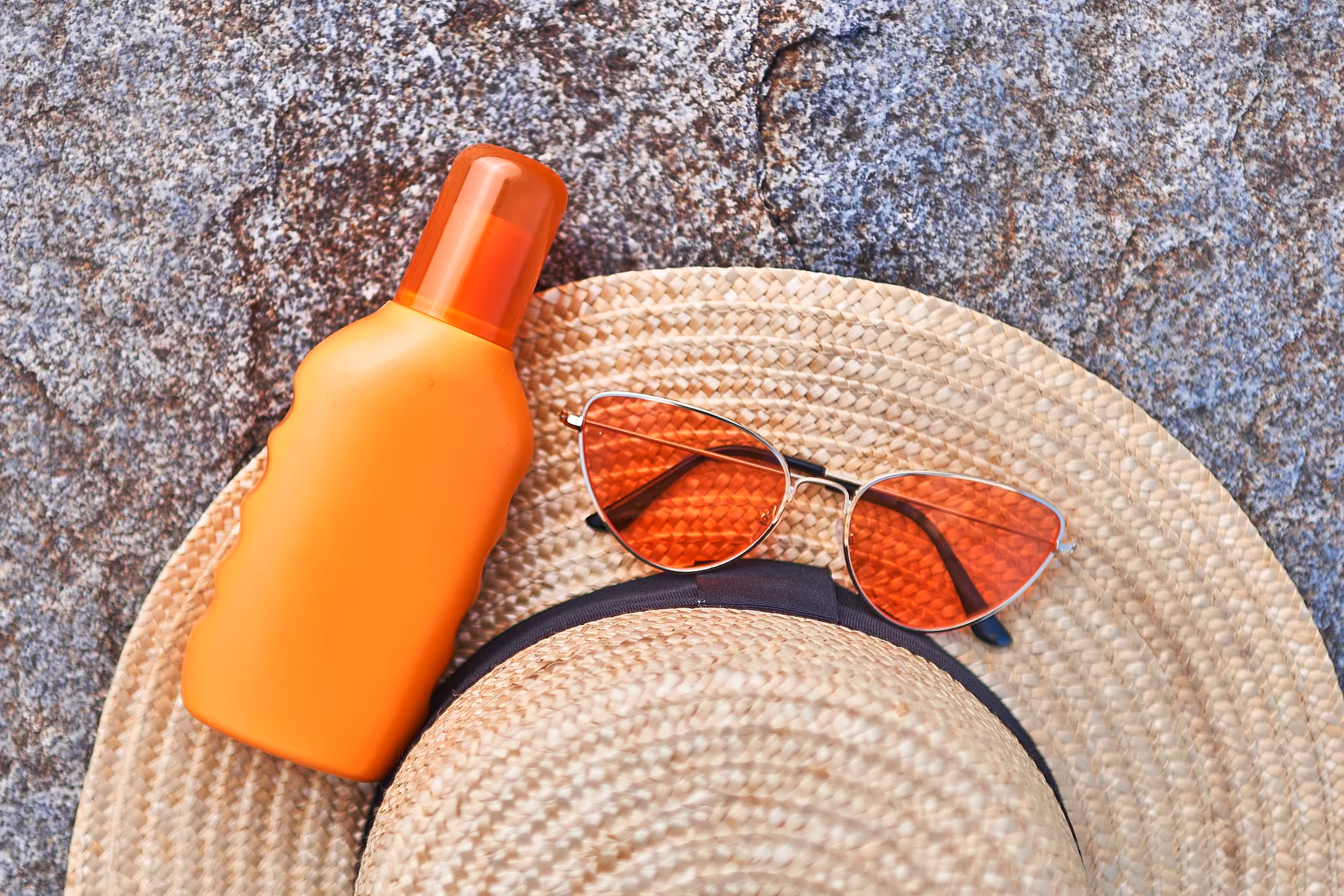 Wide-brim hat, sun glasses, and sunscreen bottle.