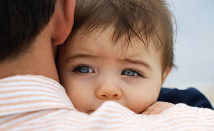 Baby resting on parent's shoulder.