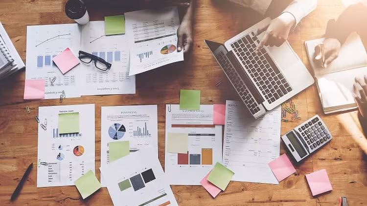 Data Analysis Table with laptop, and papers with graphs on them—all images indicating a data analysis meeting taking place.