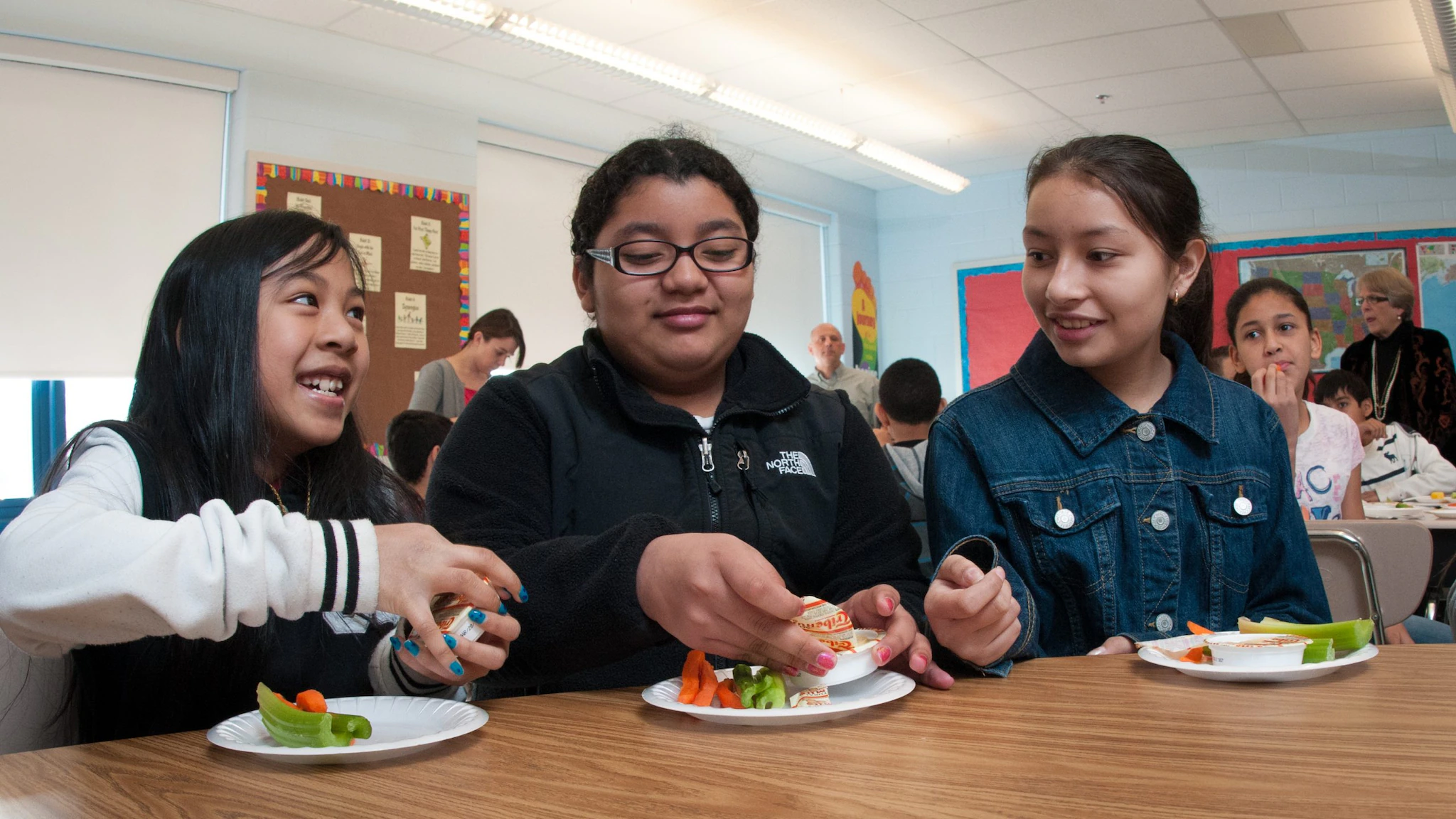 Students taste testing Students tasting raw vegetables with hummus in a school cafeteria.