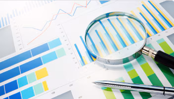 Photo of a magnifying glass with charts on a table.