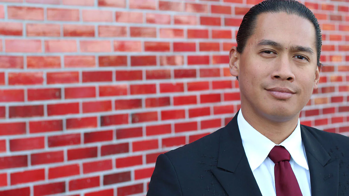 aapi man A young man in a suit in front of a brick wall