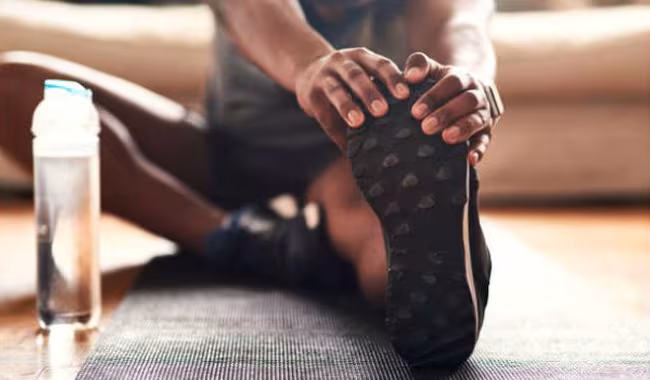 person stretching and holding foot