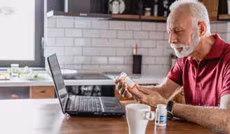 man reading prescription label in his kitchen