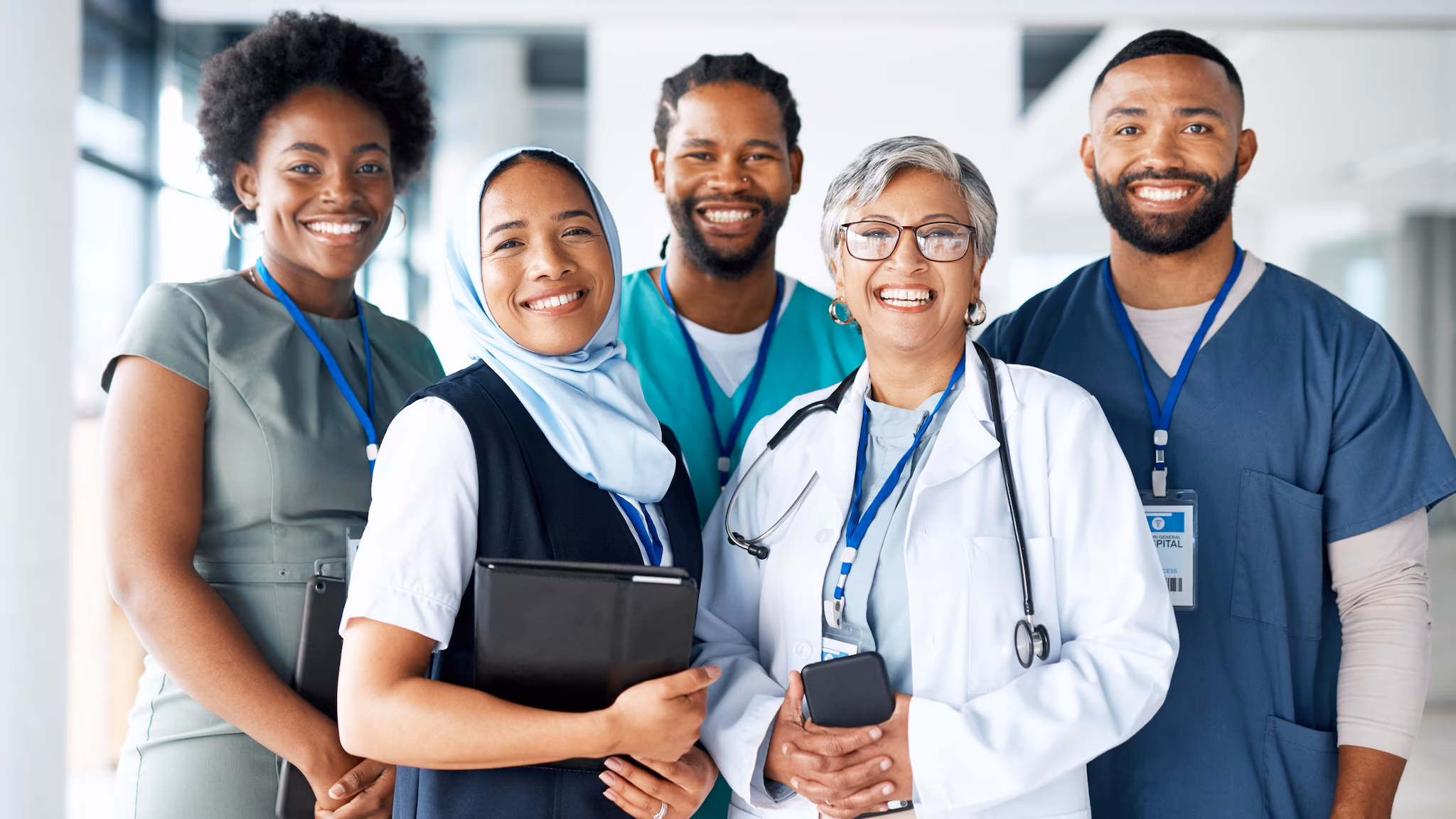 A diverse group of healthcare providers standing together for a photo, representing different ages, races, and ethnicities.