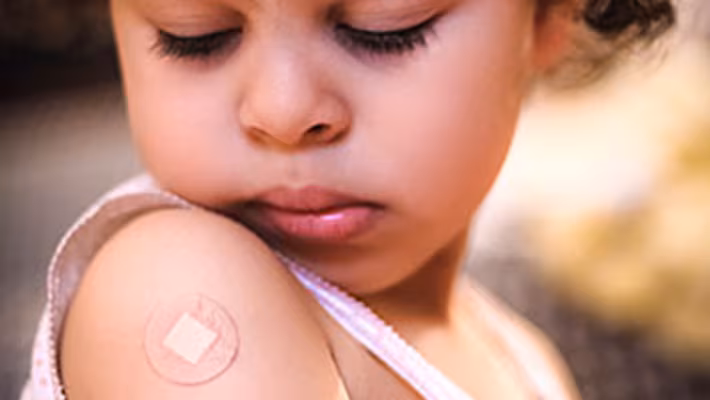 Little girl with band-aid on arm A little girl looking at the band-aid on her right shoulder from where she got a vaccine.
