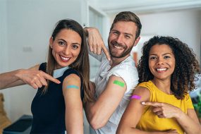 un grupo de adultos mostrando los brazos después de vacunarse