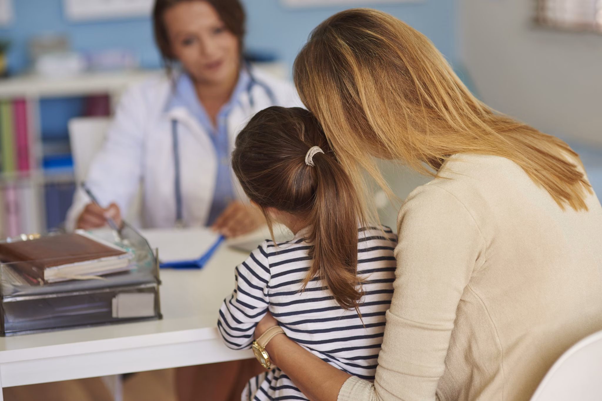 A mother and young daughter talking to a doctor.