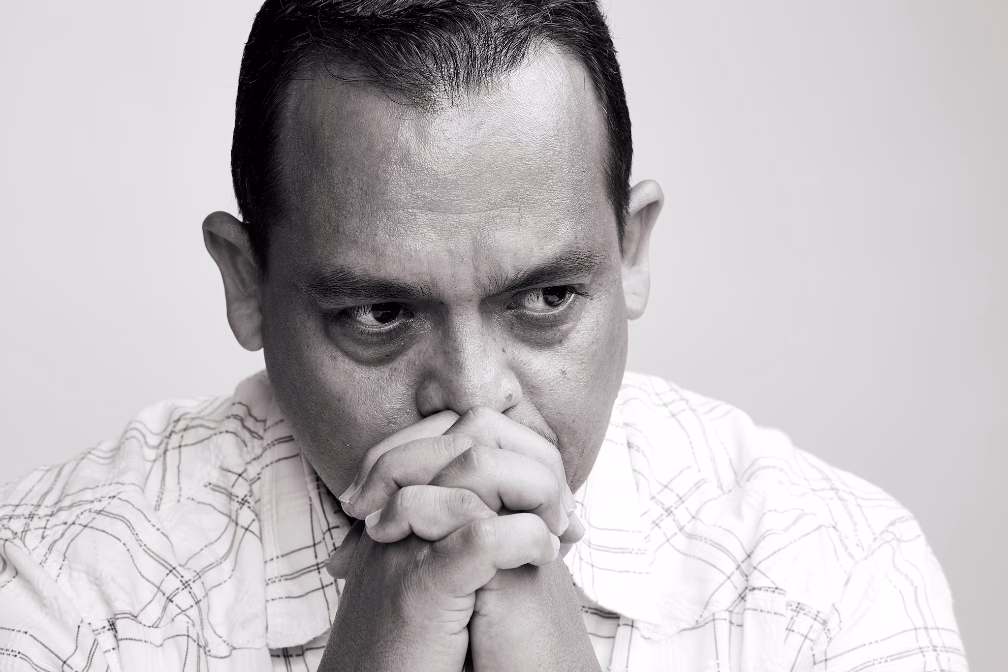 Portait of a man with his hands clasped together in front of his face