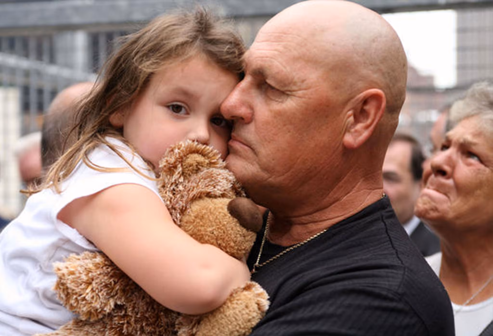 A man holding a young girl and stuffed animal at a rally.