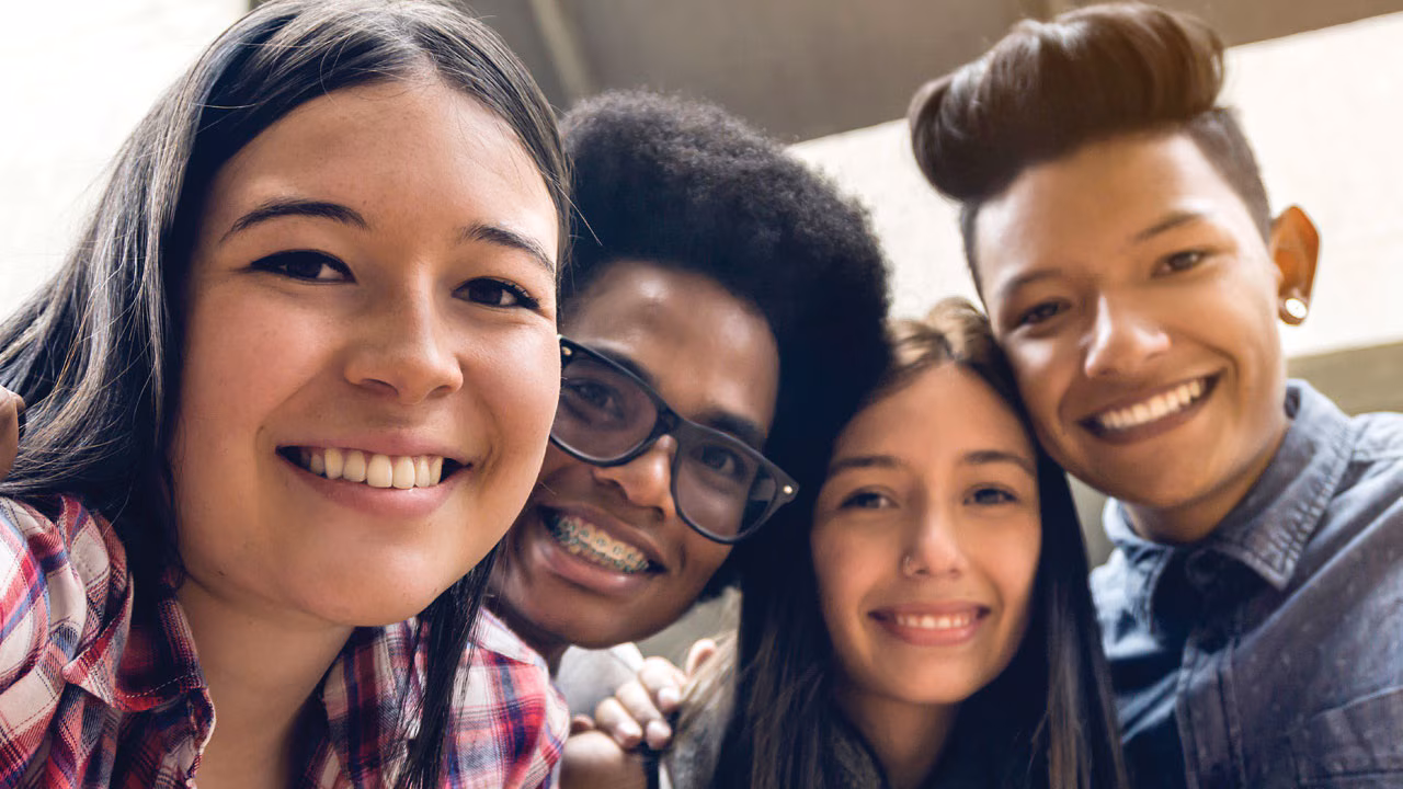 Four teenagers smiling.